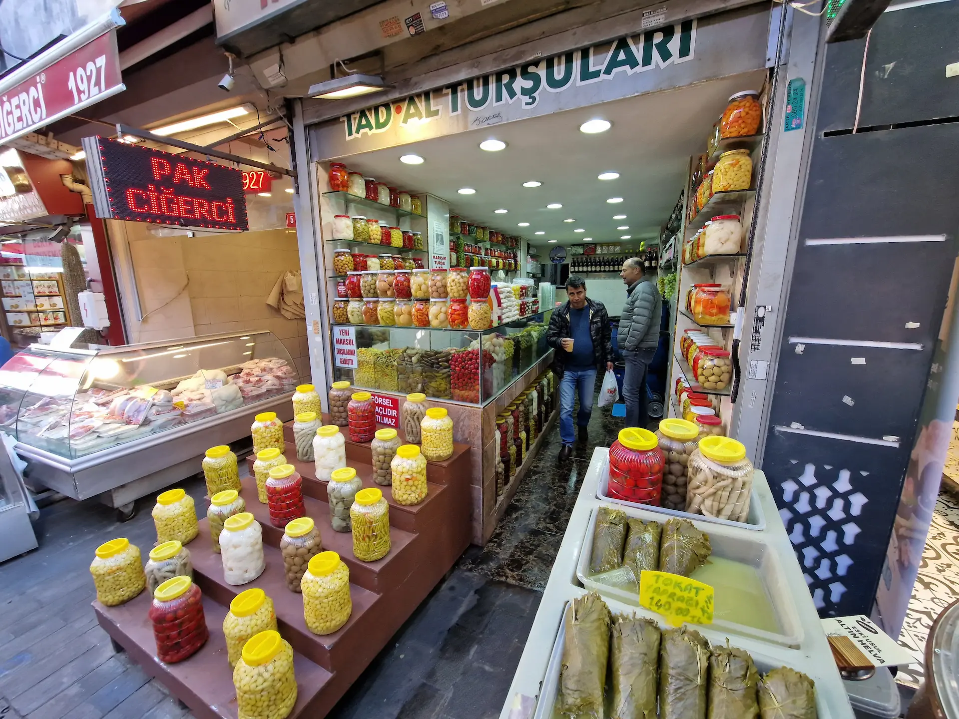 Des conserves colorées devant une échoppe spécialisée du marché de Kadıköy. Un homme sort du magasin avec un sac en plastique à la main,
