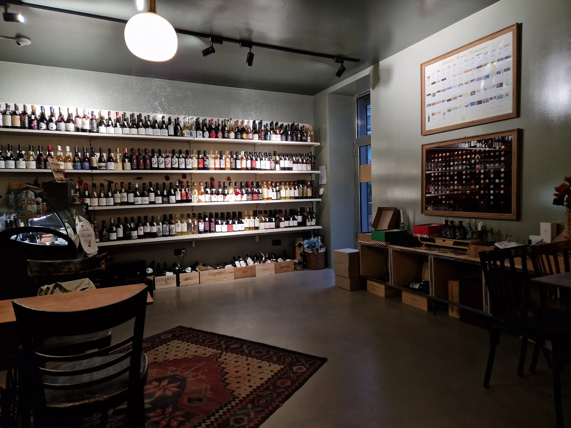 Entrée du bar à vin, un mur entier est rempli de bouteilles au fond de la pièce.