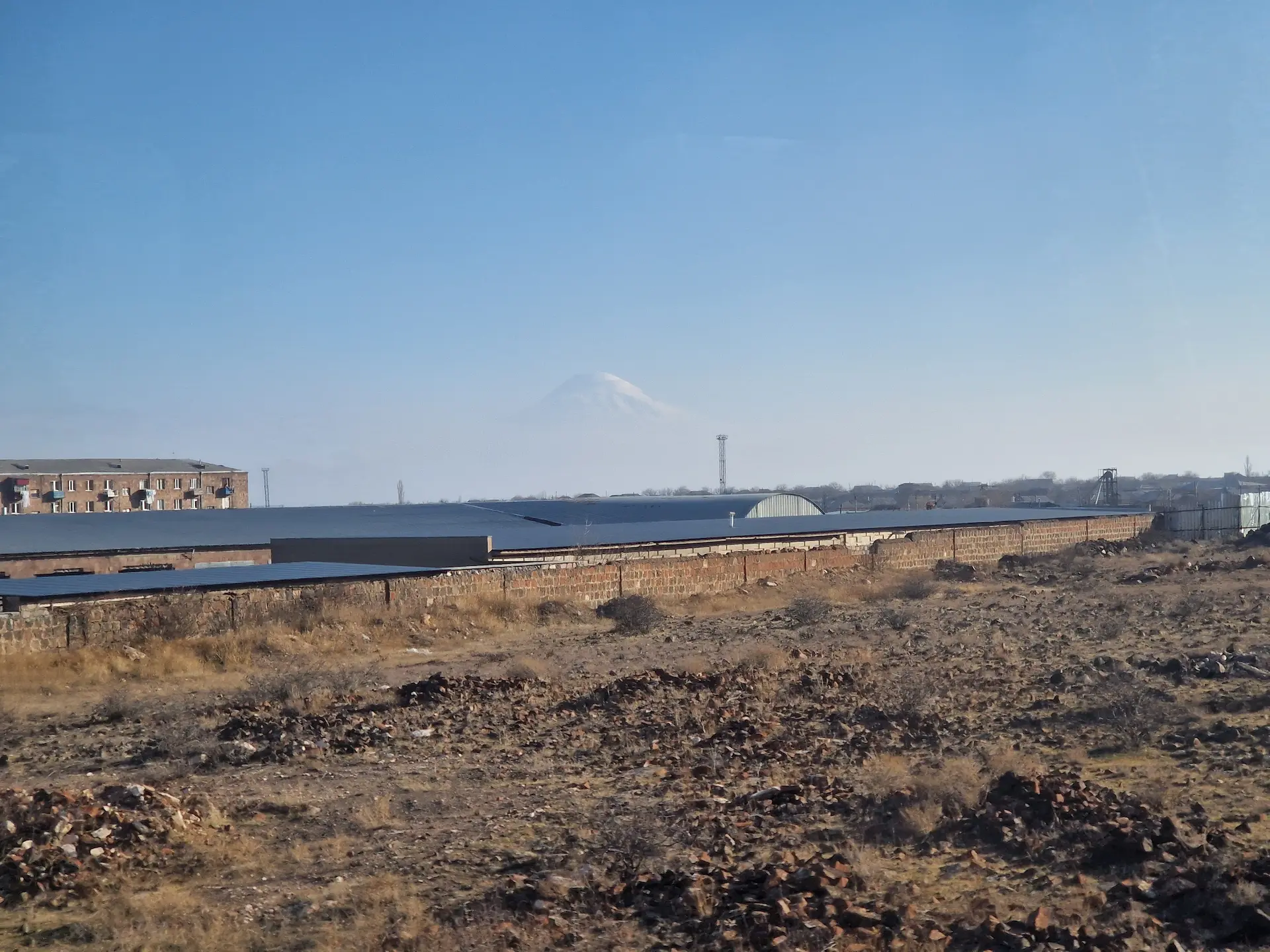 Vue du mont Ararat depuis le train, la montagne enneigée a l'air de flotter au loin, derrière le plateau arménien.