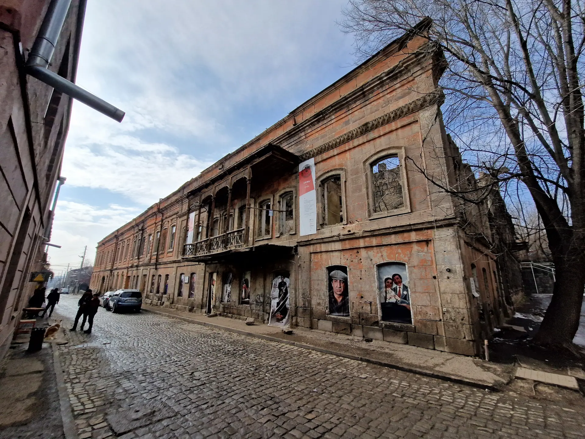 Un immeuble à moitié en ruines, avec un grand balcon en bois sur rue. Des images du film 'Le tango de notre enfance' couvrent les fenêtres.