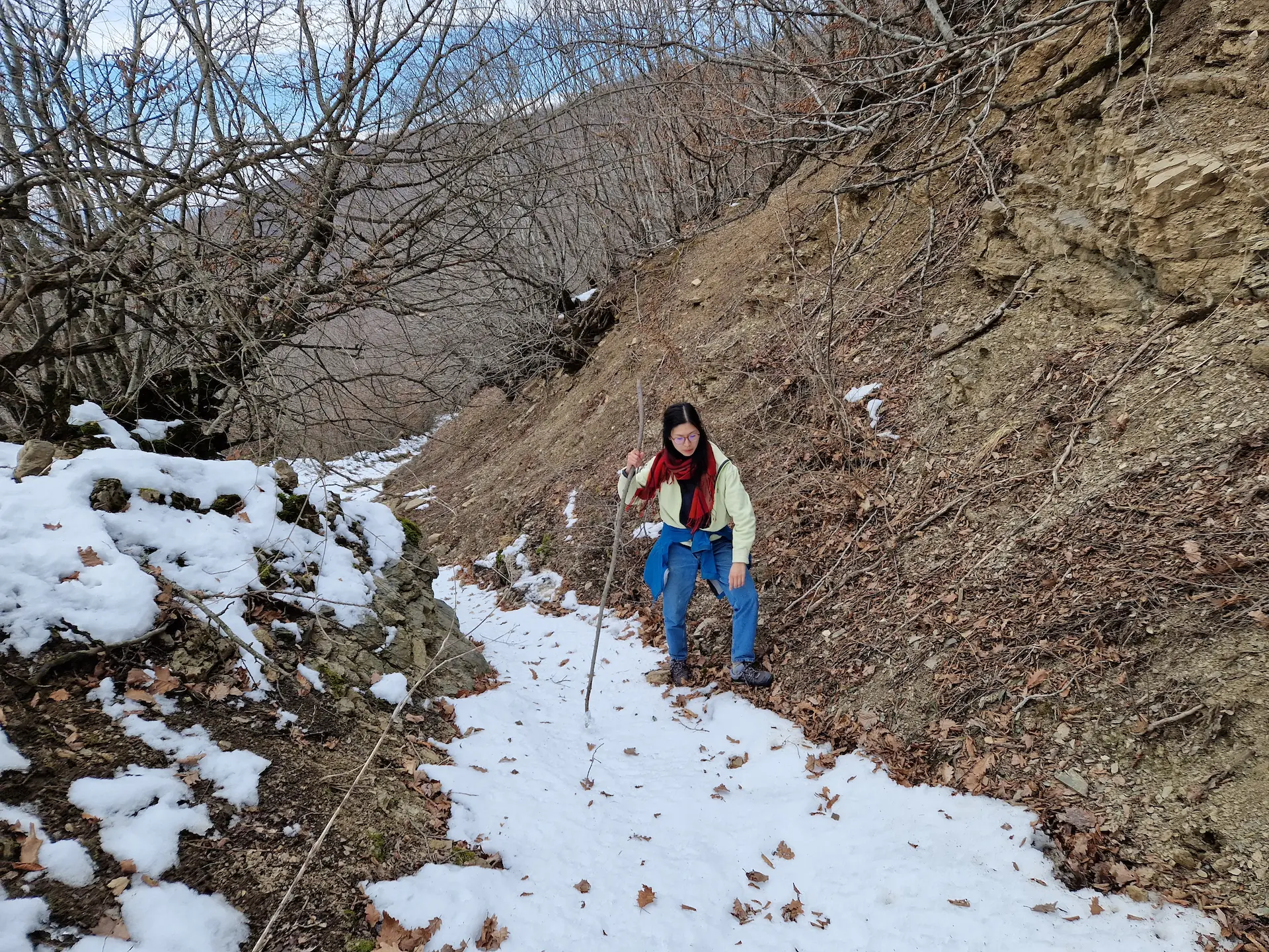 Clara, un bâton dans la main, tente de marcher sur le côté d'un chemin complètement recouvert de neige.