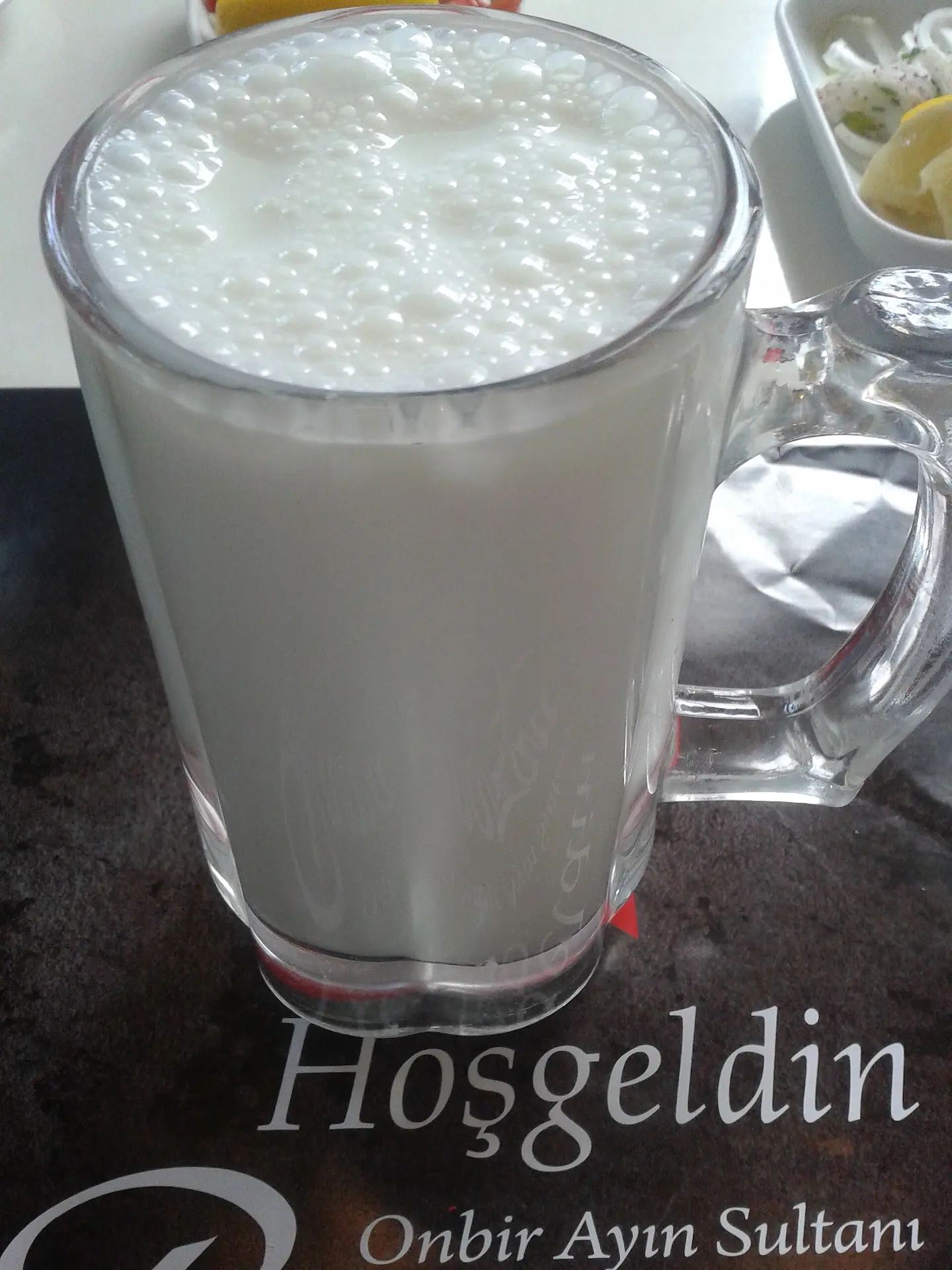 Boisson à base de lait, servi dans une tasse en verre et mousseux sur le dessus.
