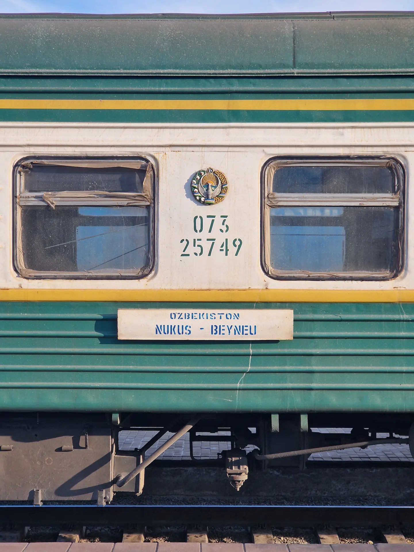 Profil de notre vieux train vert et jaune. Dessus, on lit 'Ozbekistan, Nukus - Beyneu'.