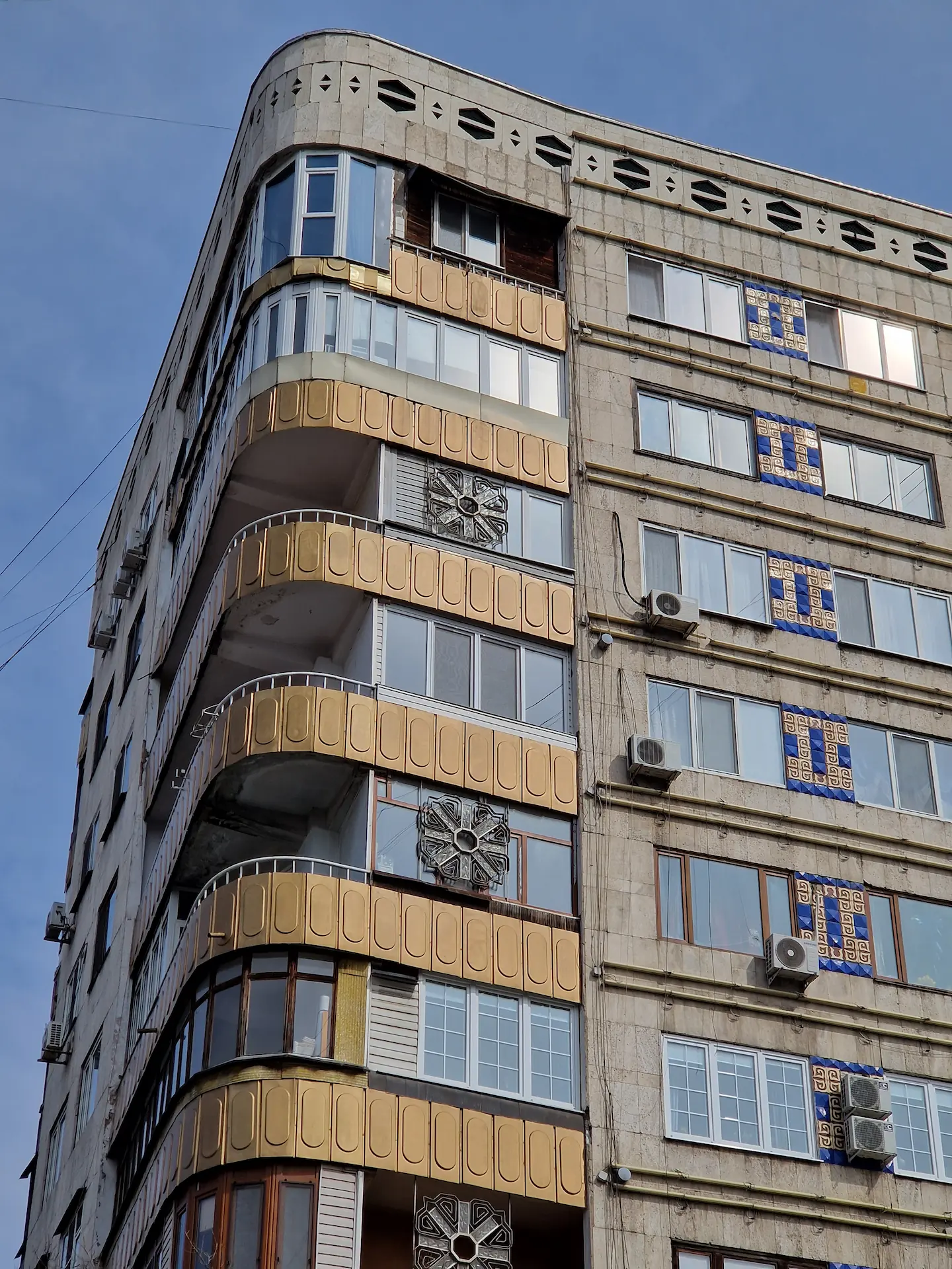 Un grand immeuble avec des balcons arrondis et dorés dans les angles