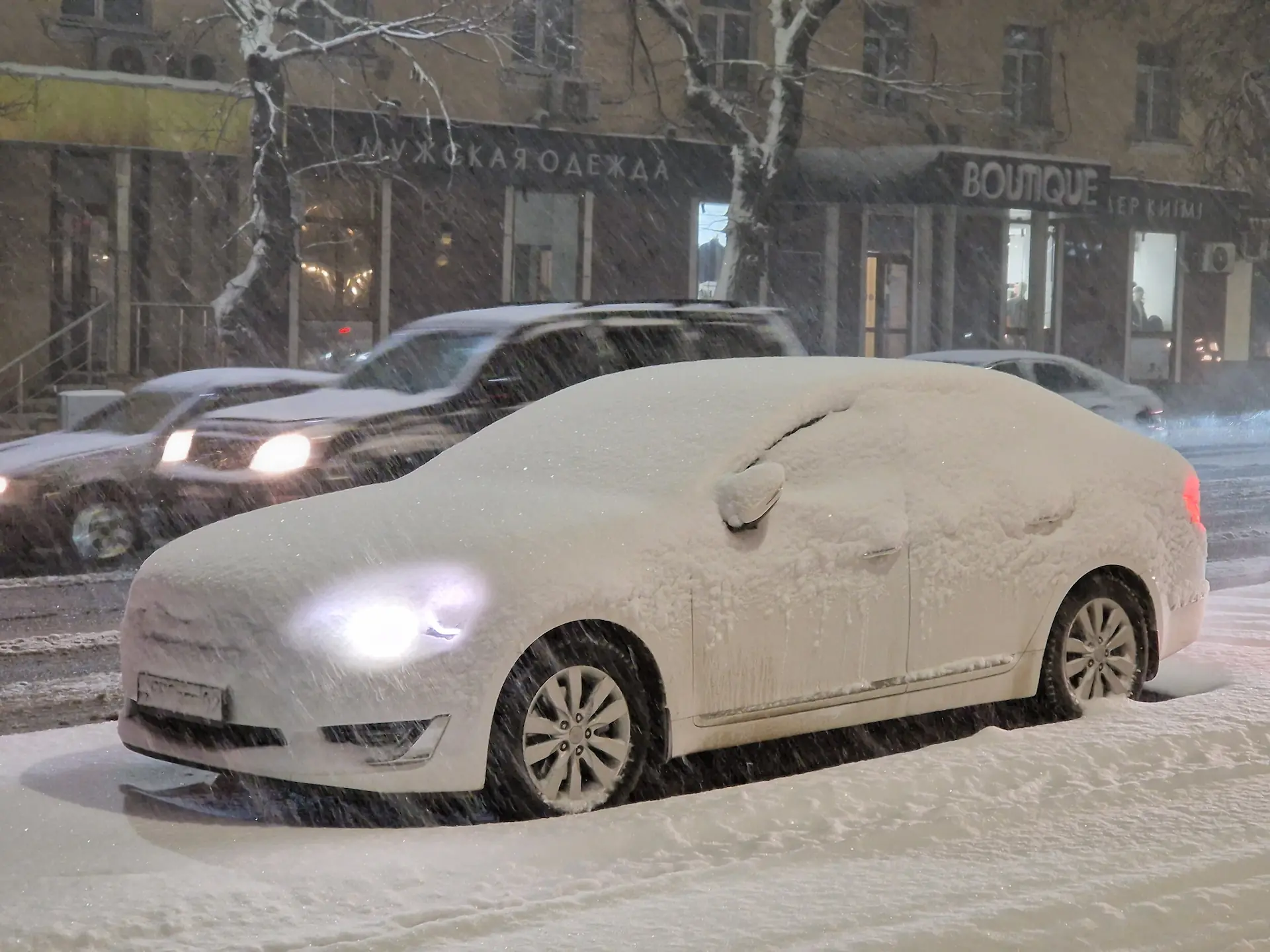 Une voiture dont les phares brillent derrière une couche de neige